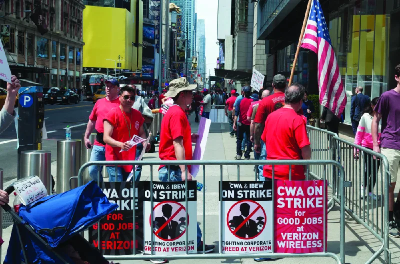 Figure 6.13 Union workers from the Communications Workers of America and the International Brotherhood of Electrical Workers are shown walking a Verizon picket line. They are protesting Verizon’s decision to not provide pay raises. (credit: modification of “Verizon on Strike” by Marco Verch/Flickr, CC BY 2.0)